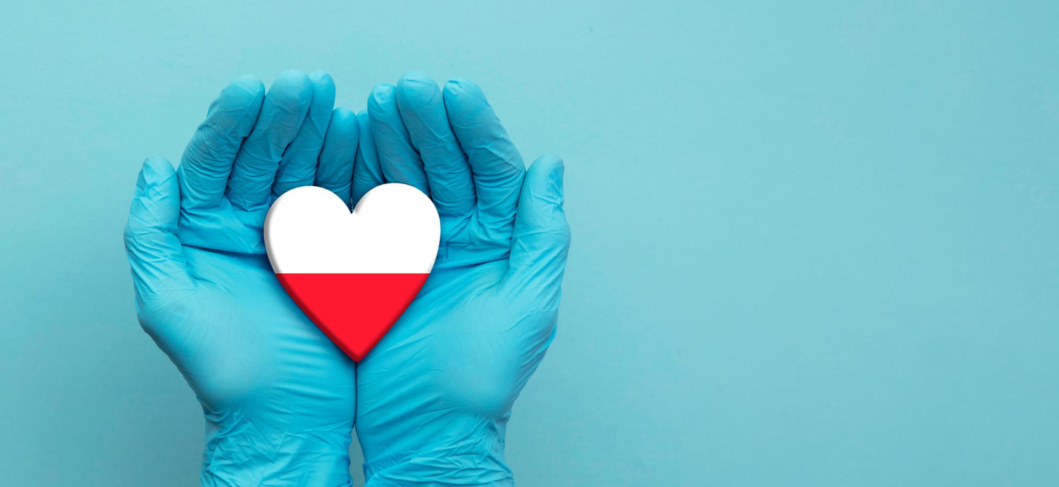 Guantes de protección sosteniendo un corazón con los colores polacos, representando la sanidad y la educación médica en Polonia
